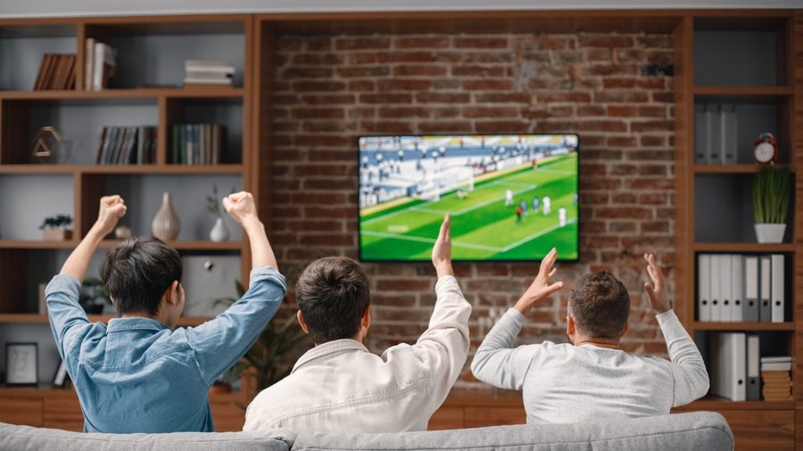 Viewers watching a football match on a television with an on-screen score display